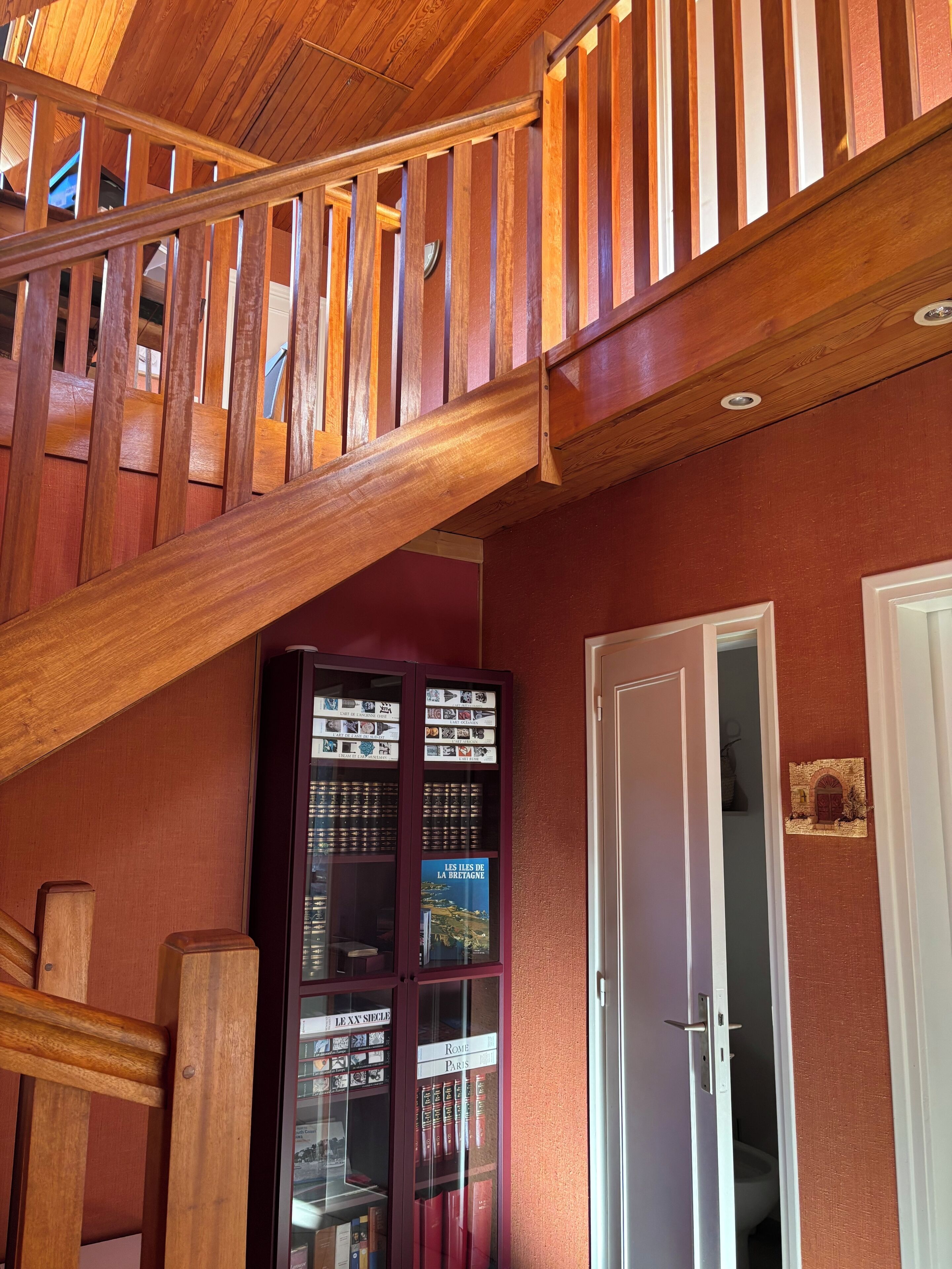 A wooden staircase with a glass display case below.
