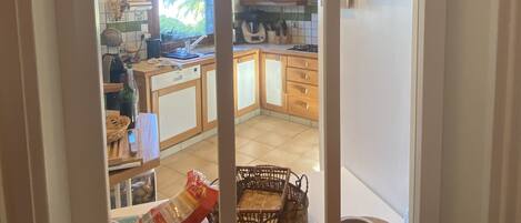 A kitchen with wooden cabinets, a dining area with a table and chairs, and a view through a window.