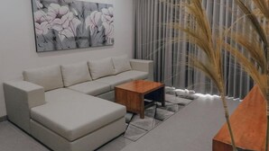 Una sala de estar moderna con un sofá modular, una mesa de centro de madera y un cuadro abstracto grande en la pared.