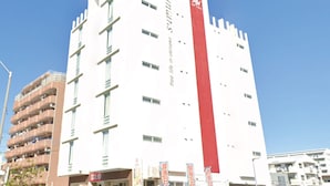 Un grand bâtiment blanc, orné d’une bande verticale rouge et doté de nombreuses fenêtres.
