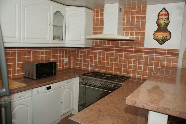 A kitchen with white cabinets, a microwave, a stove, and a tiled backsplash.
