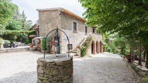 A stone building with a well-maintained garden, outdoor seating, and a central water feature. - Casale Gli Angeli - Villa with Garden and Parking (Gubbio)