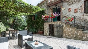 A stone building with a balcony, outdoor seating area, and potted plants. - Casale Gli Angeli - Villa with Garden and Parking (Gubbio)