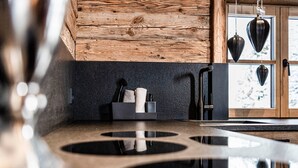 A kitchen with a wooden ceiling, a black countertop, and hanging kitchen utensils.
