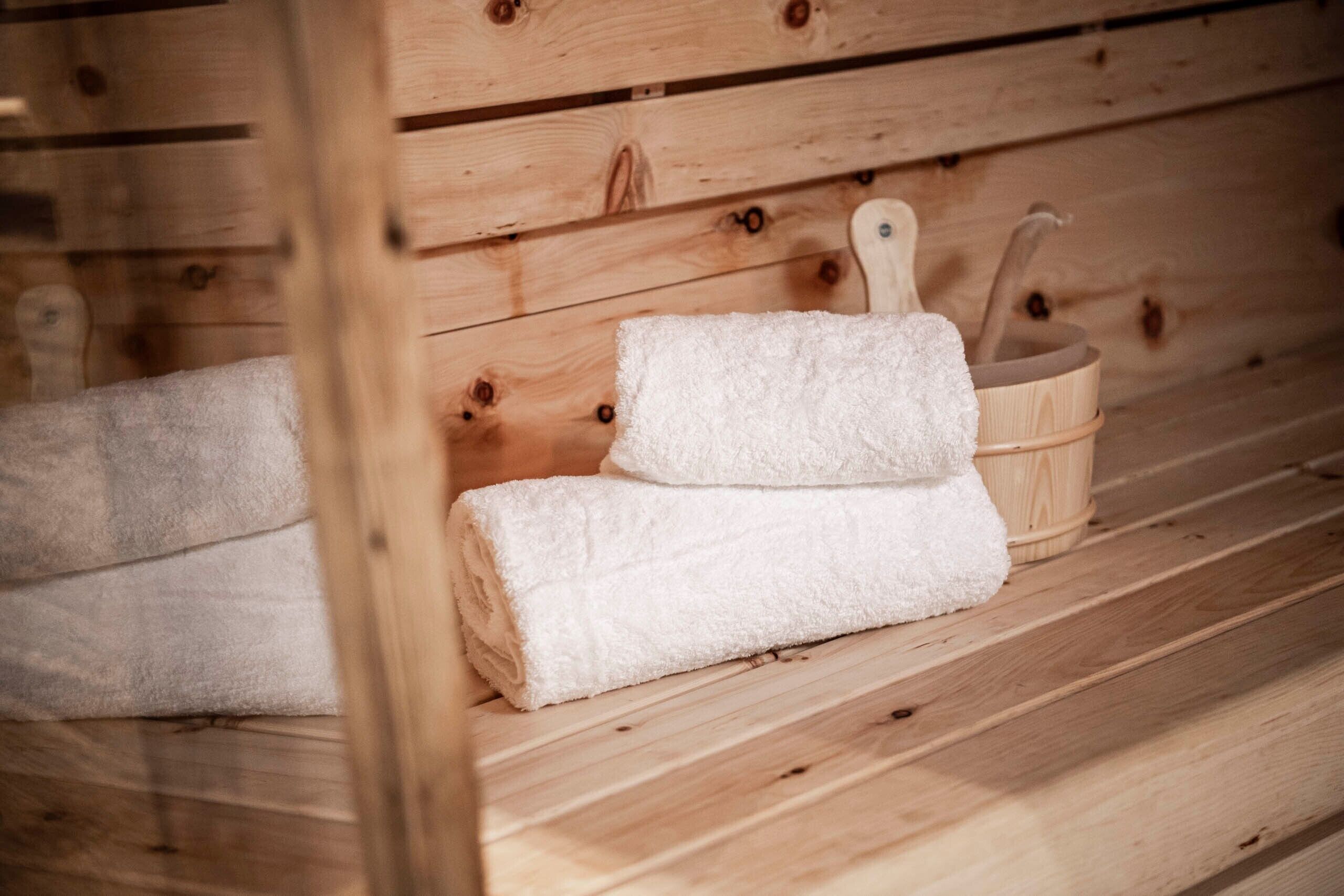 A wooden bench with a folded towel and a wooden bucket.