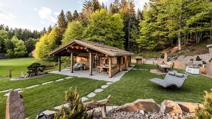 A wooden cabin with a patio, surrounded by a well-maintained lawn and trees.