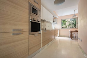 A modern kitchen with wooden cabinets, stainless steel appliances, and a dining area with a table and chairs.