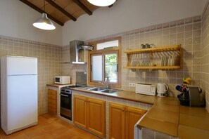A kitchen with a refrigerator, microwave, stove, sink, and wooden cabinets.