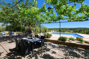 An outdoor patio with a table and chairs, a pool, and a view of the hills. - Casa Son Fornes with Pool, Wi-Fi, Garden, Terrace and Parking (ALGAIDA)