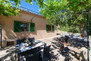 A patio with a table set for dining, outdoor furniture, and a barbecue grill.