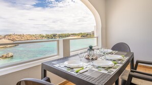 A dining table set with plates, glasses, and cutlery, overlooking a coastal view. - Apartment "White Sands 306" on the Beach with Sea View, Pool (Arenal d'en Castell)
