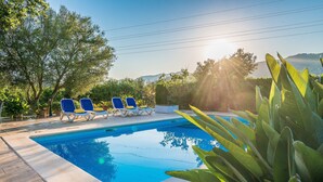 A swimming pool with lounge chairs, surrounded by greenery and a clear sky. - Villa 'Can Tonet' with Mountain View, Wi-Fi and Air Conditioning (Port de Pollença)