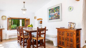 A dining area with a wooden table, chairs, a chandelier, and a painting on the wall. - Villa 'Can Tonet' with Mountain View, Wi-Fi and Air Conditioning (Port de Pollença)