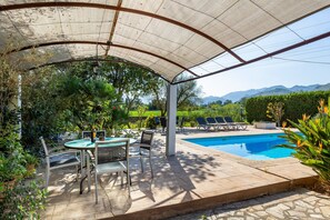 Un espace extérieur abrité comprenant une piscine, des chaises longues et une table avec des chaises.