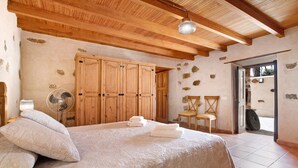 A bedroom with a wooden ceiling, a bed with a quilt, a wooden wardrobe, a fan, and a chair. - "Casa Rural Andresito" with Mountain Views, Pool, Wi-Fi, and Terrace (Pájara)