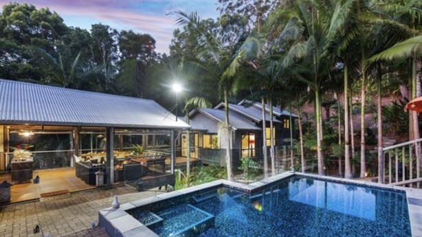 A pool area with a clear view of the surrounding landscape, including a house with a covered patio and a well-maintained lawn. - 2 x queen bedrooms, 2 x ensuite's, 1 guest lounge, outdoor bbq kitchen and pool. (Currumbin Valley)