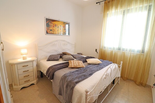 Une chambre à coucher avec un lit, une table de chevet, une lampe et un tableau au mur.