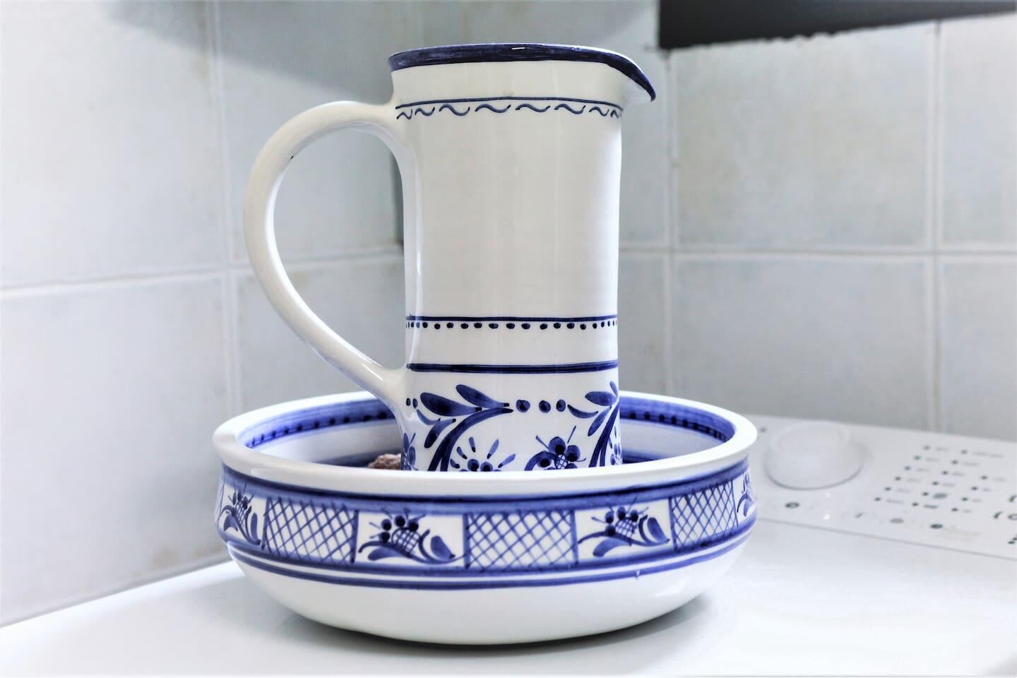 Un pichet blanc orné de motifs bleus et un bol assorti, tous deux posés sur un comptoir blanc.