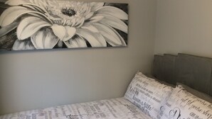 A bedroom with a large floral artwork on the wall, a bed with a printed pillowcase, and a headboard.