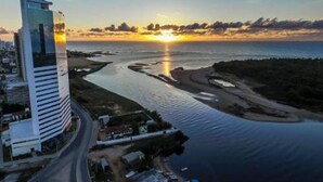 A modern hotel with a view of the sunset over a body of water. - Tryp Pernambuco (Jaboatao dos Guararapes)