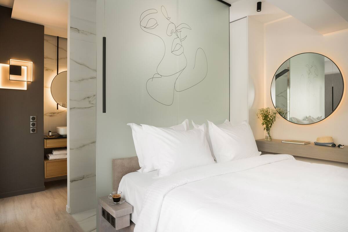 Une chambre à coucher moderne avec un lit, une table de chevet et un miroir fixé au mur.