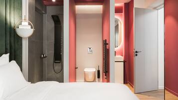 Un dormitorio moderno con una cama grande, ducha y baño con inodoro y lavabo.