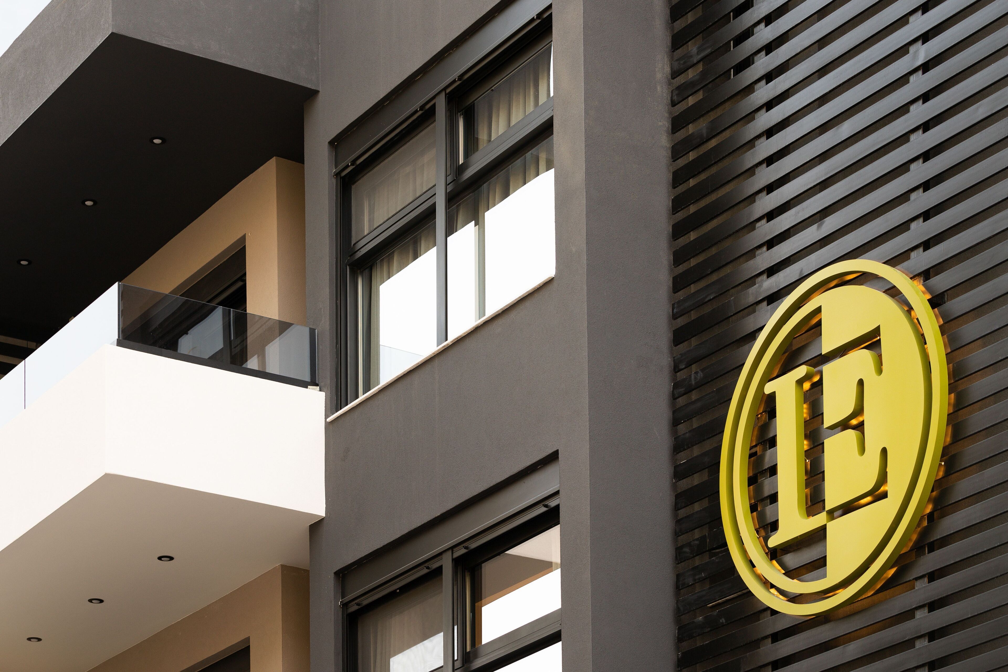 A building facade with a prominent golden 'E' logo, large windows, and a modern architectural design.