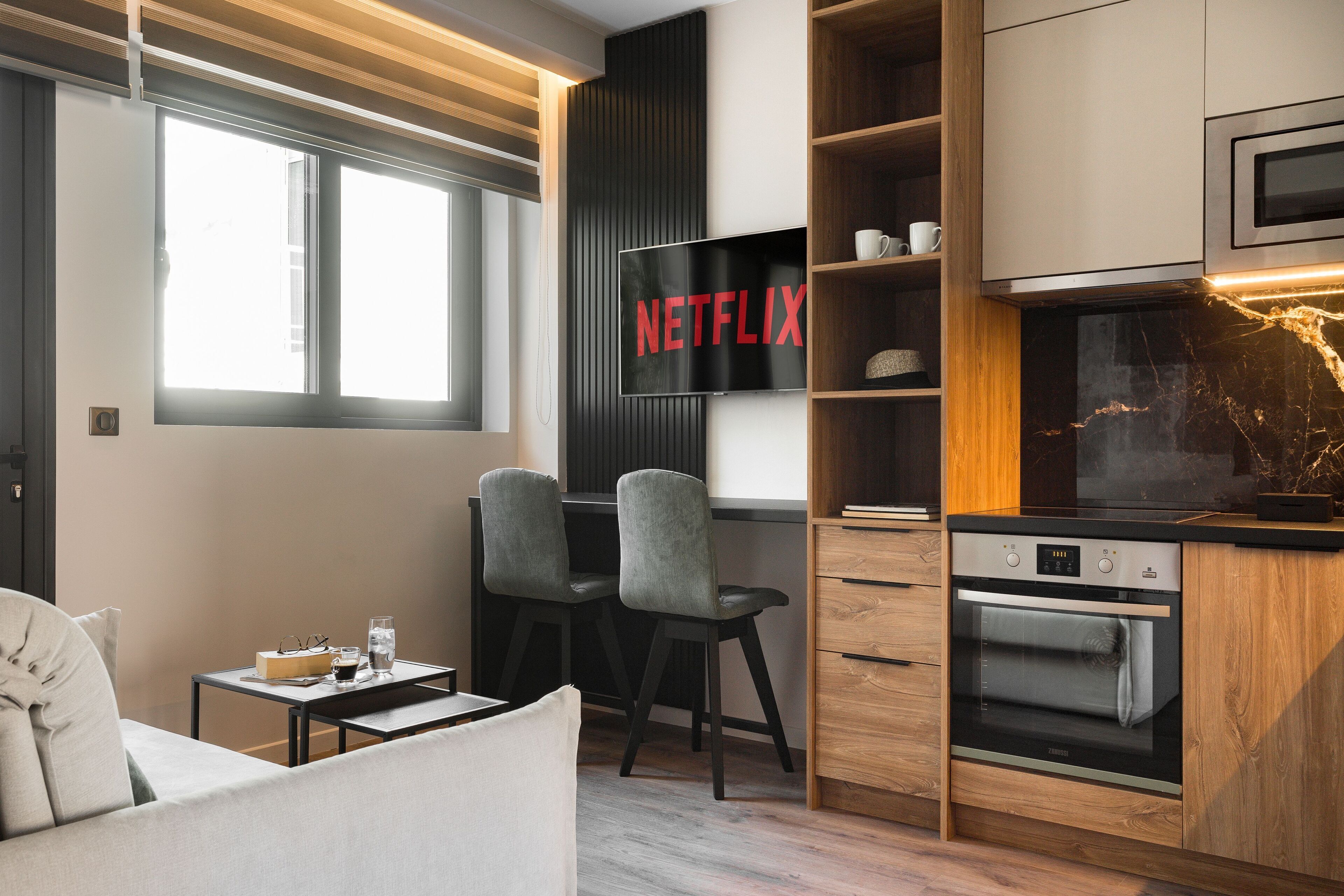 A modern kitchen with a built-in oven, a microwave, and a wooden cabinet.