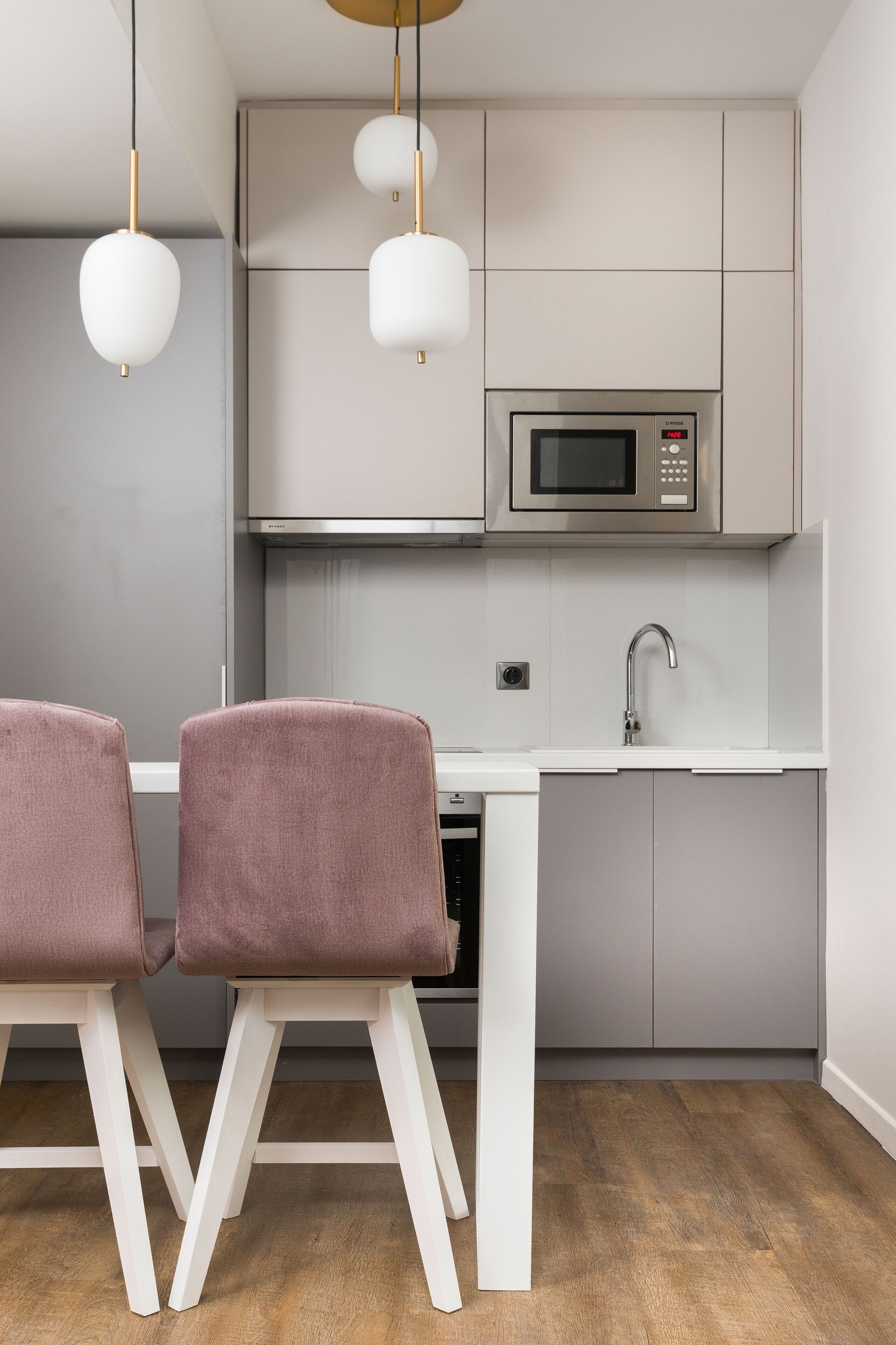 A modern kitchen with a microwave, sink, and two chairs.