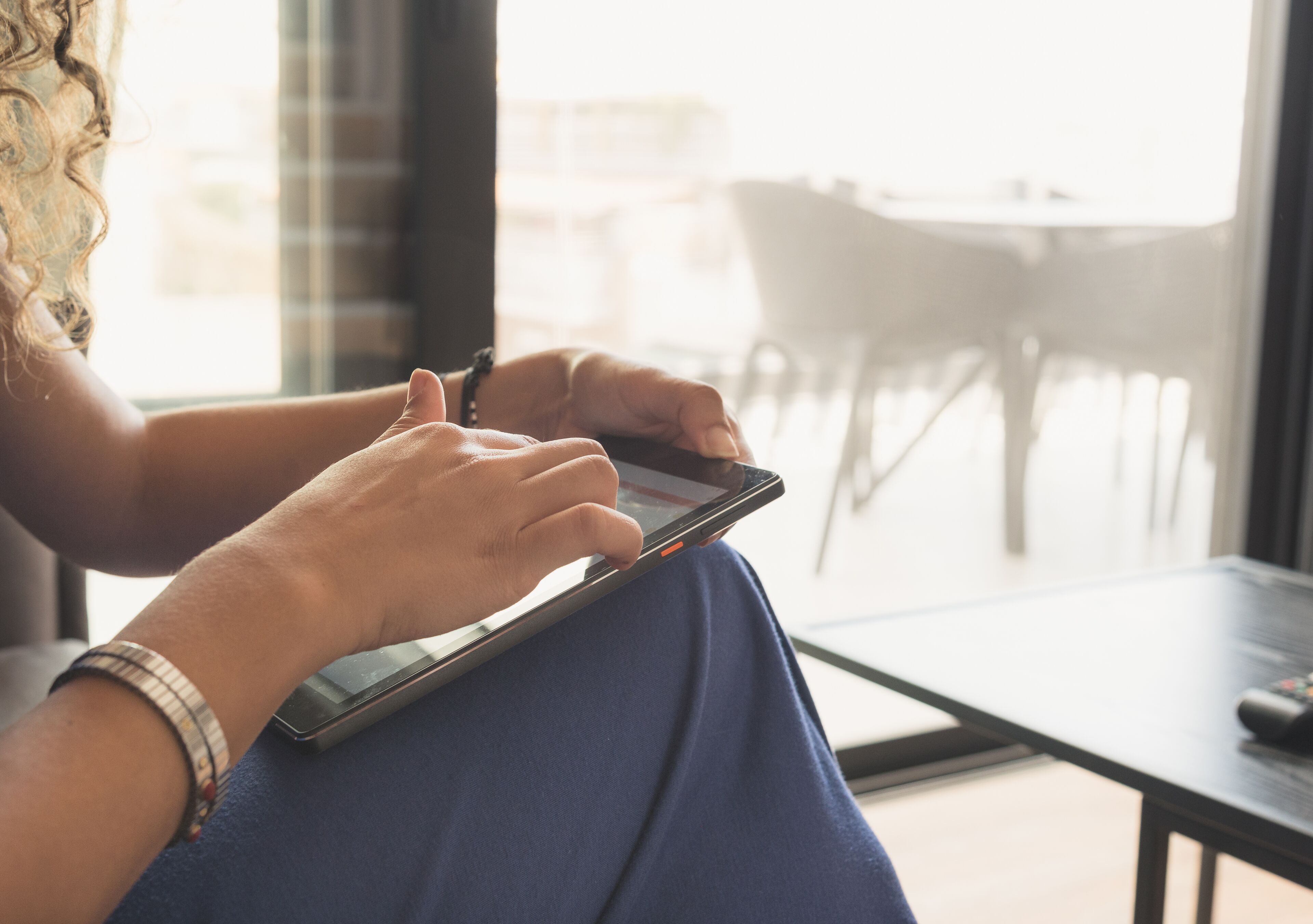Uma pessoa sentada à mesa com um tablet, usando um relógio e uma pulseira.