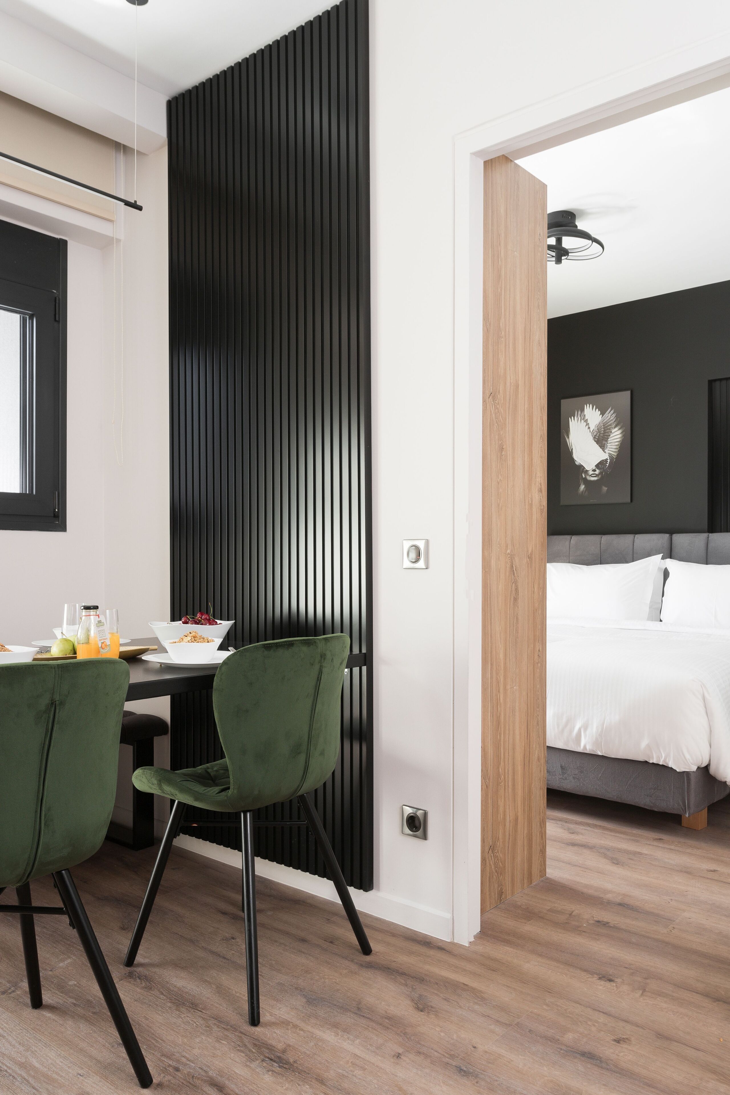 Un dormitorio moderno con una cama, una mesita de noche con lámpara y vistas a un comedor con sillas y una mesa.