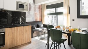 A modern kitchen with a built-in microwave, a wooden island, and a dining area with a table and chairs. - LUX&EASY Athens Downtown Apartments (Athens)
