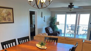 A dining area with a wooden table and chairs, a chandelier, and a view of a balcony with outdoor furniture. - Can't Beat the View! (Camdenton)