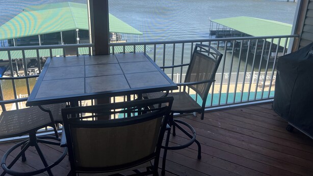 A deck with a table and chairs, overlooking a body of water with a bridge in the distance. - Can't Beat the View! (Camdenton)