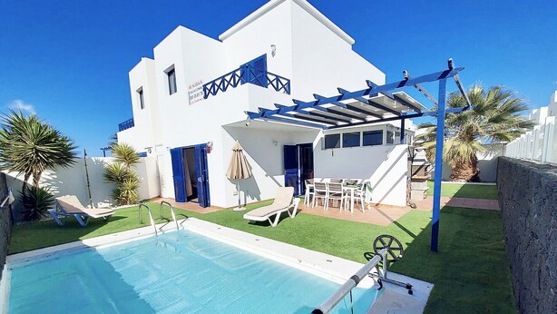 Ein weißes Gebäude mit Pool, Außenbereich und einer Pergola.