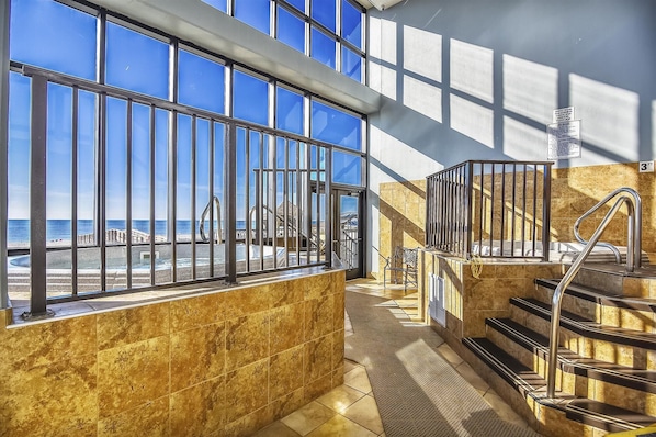 A high-rise hotel interior with a view of the beach, a staircase, and a railing.