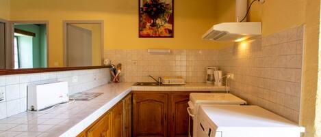 A kitchen with wooden cabinets, a white countertop, a built-in dishwasher, and a tiled backsplash.
