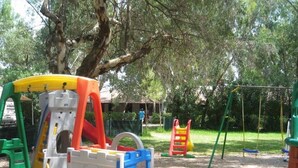 Un parque infantil con diversas estructuras de juego, incluyendo un tobogán, una pared de escalar y columpios.