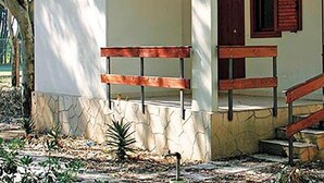 Un pequeño edificio con fachada blanca, una banca de madera y una escalera que lleva a un nivel superior.