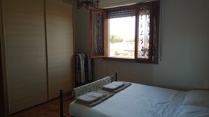 A bedroom with a bed, a wardrobe, and a window with curtains.