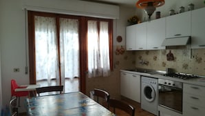 A compact kitchen with a washing machine, a stove, and a dining area with a table and chairs.