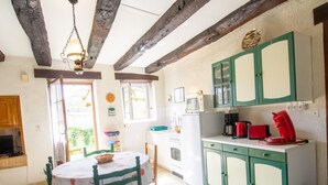 A kitchen with a dining table, chairs, a refrigerator, a microwave, and green cabinets.
