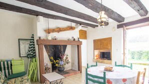 A cozy room with a wooden table and chairs, a sofa, a fireplace, and a television.