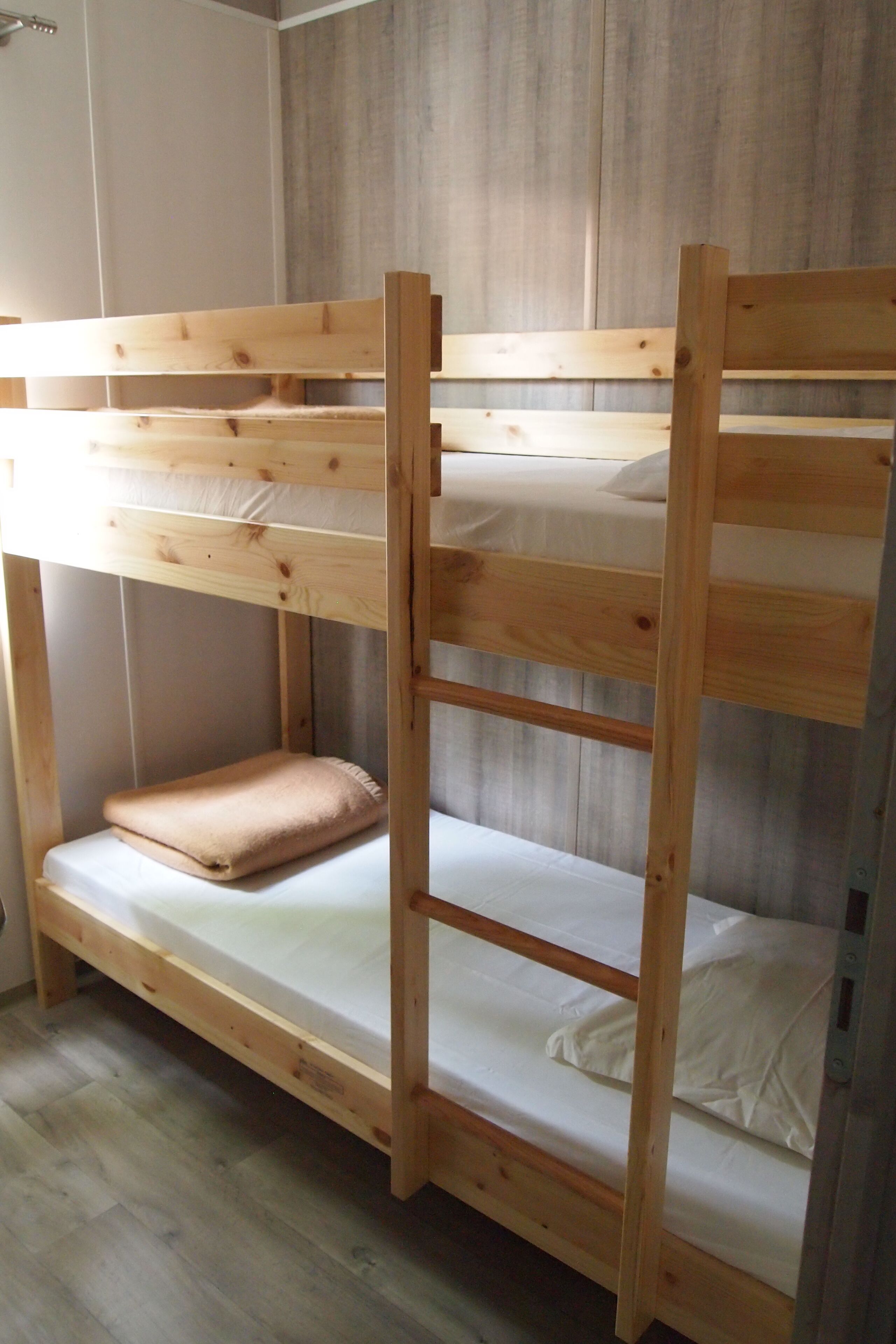 Una cama litera con estructura de madera y ropa de cama blanca.