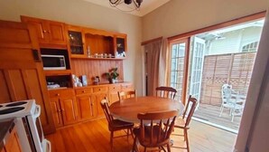 A kitchen with wooden cabinets, a microwave, and a dining table with chairs. - ✨3 Bdrm Guest Suite in 1920s Bungalow, North Shore (Auckland)