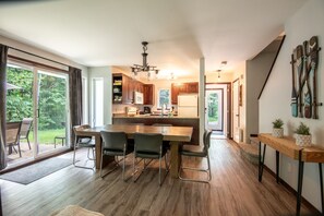 Una cocina moderna con una isla central, armarios de madera y un piso de vidrio corredera que da a un patio.