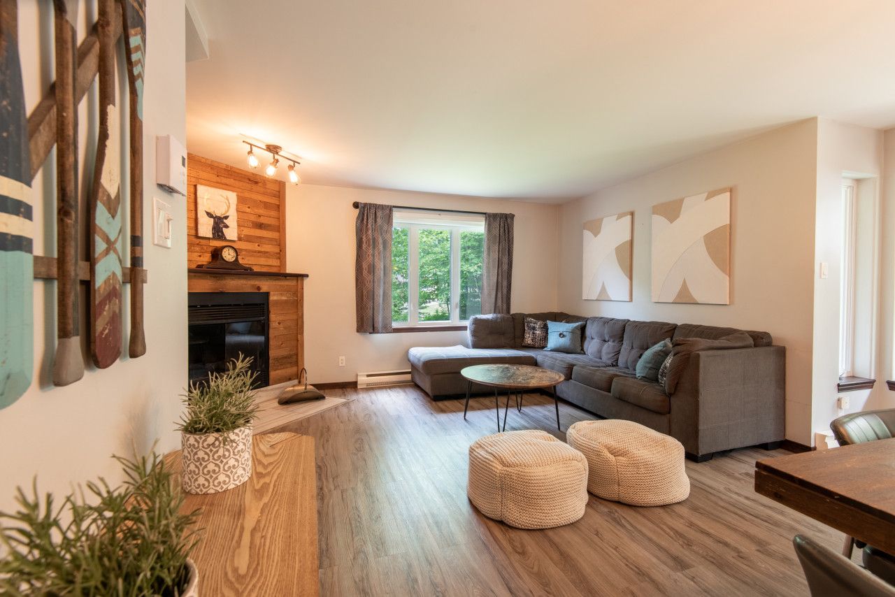 A cozy living room with a fireplace, a sofa, a coffee table, and a dining area.