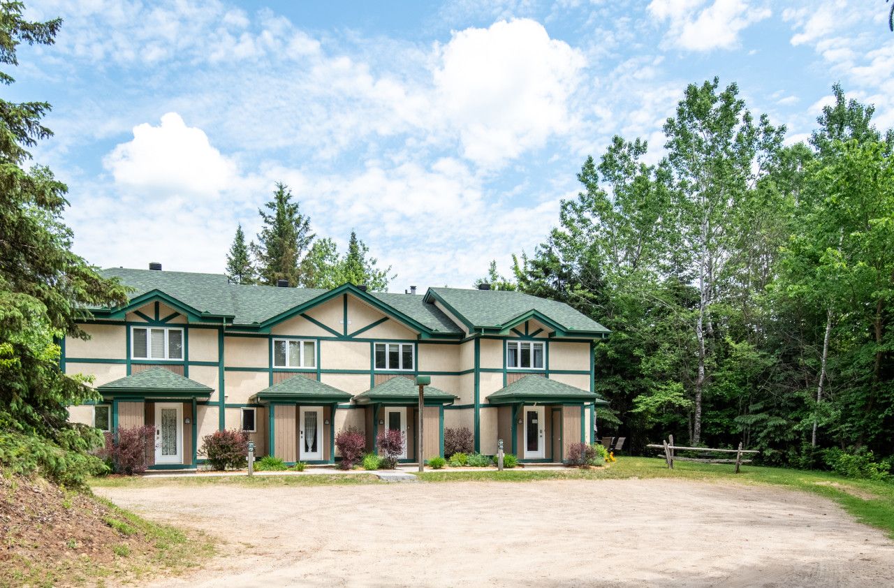 A two-story building with a symmetrical facade, multiple windows, and a green roof.