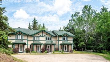 A two-story building with a symmetrical facade, multiple windows, and a green roof.