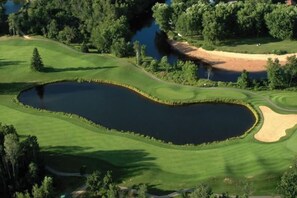 A golf course with a pond, surrounded by trees and a dirt path. - Townhouse on the Golf w/ Pool Access -Aiglon 1717 (Mont-Tremblant)
